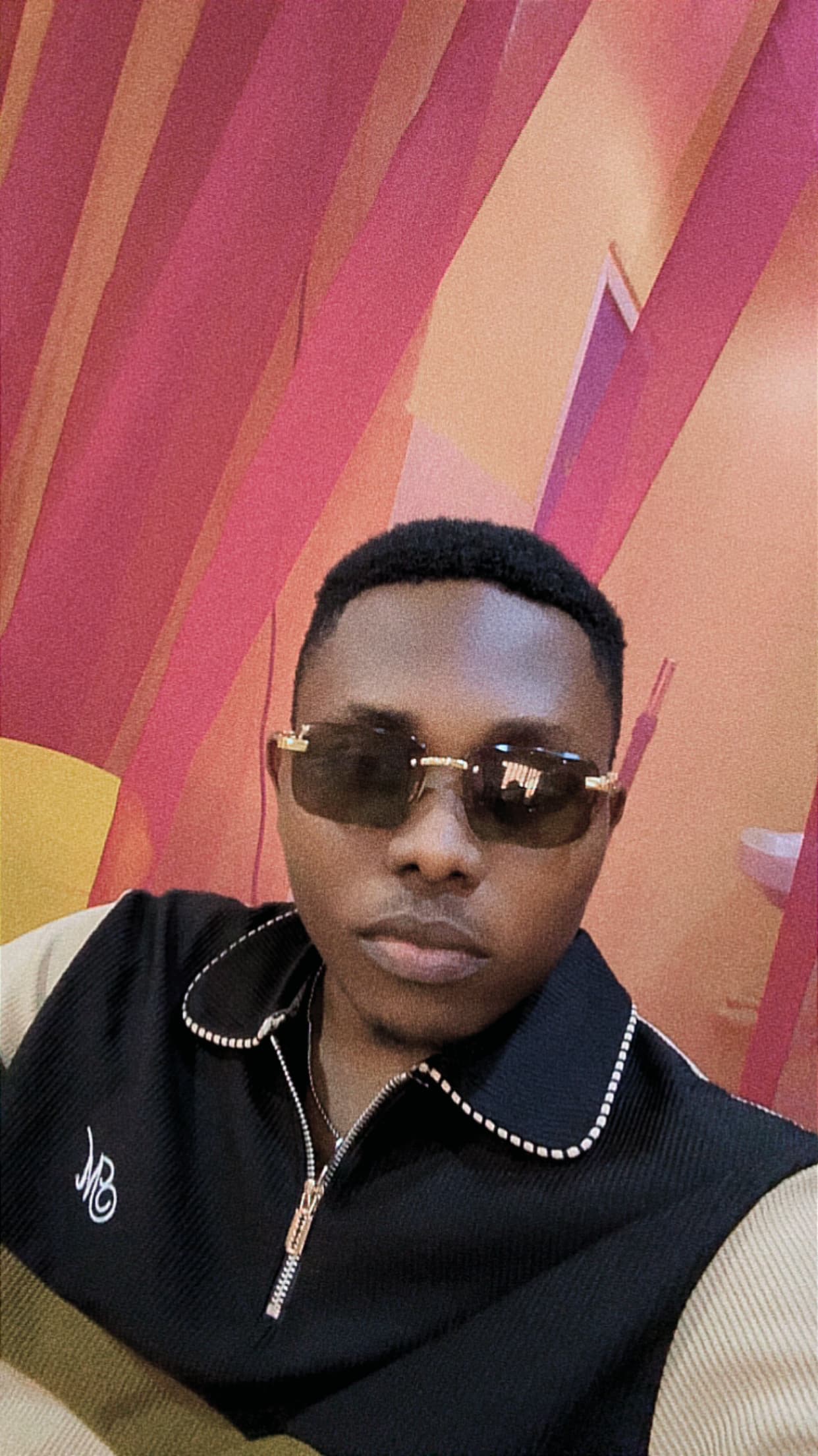 Samuel Winner in sunglasses, in front of a pink and orange wall